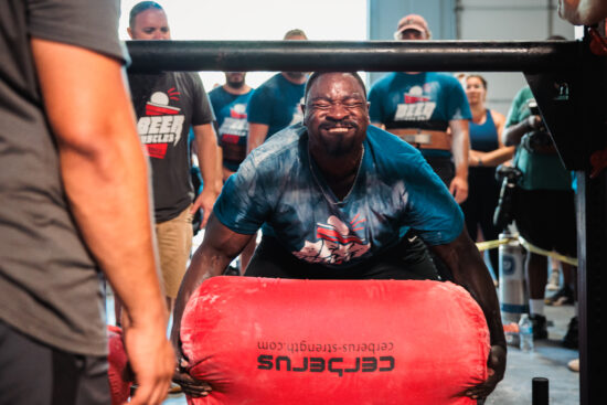 athlete attempting a max weight sandbag load over bar